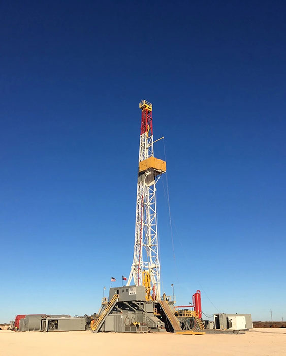 A large oil rig is sitting in the middle of a desert.